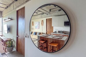 Une cuisine moderne avec un îlot central, des tabourets en bois et un grand miroir au mur.