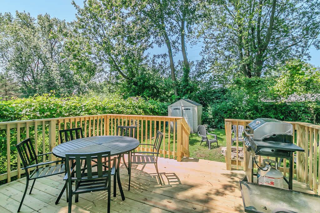 A deck with a table and chairs, a grill, and a shed.