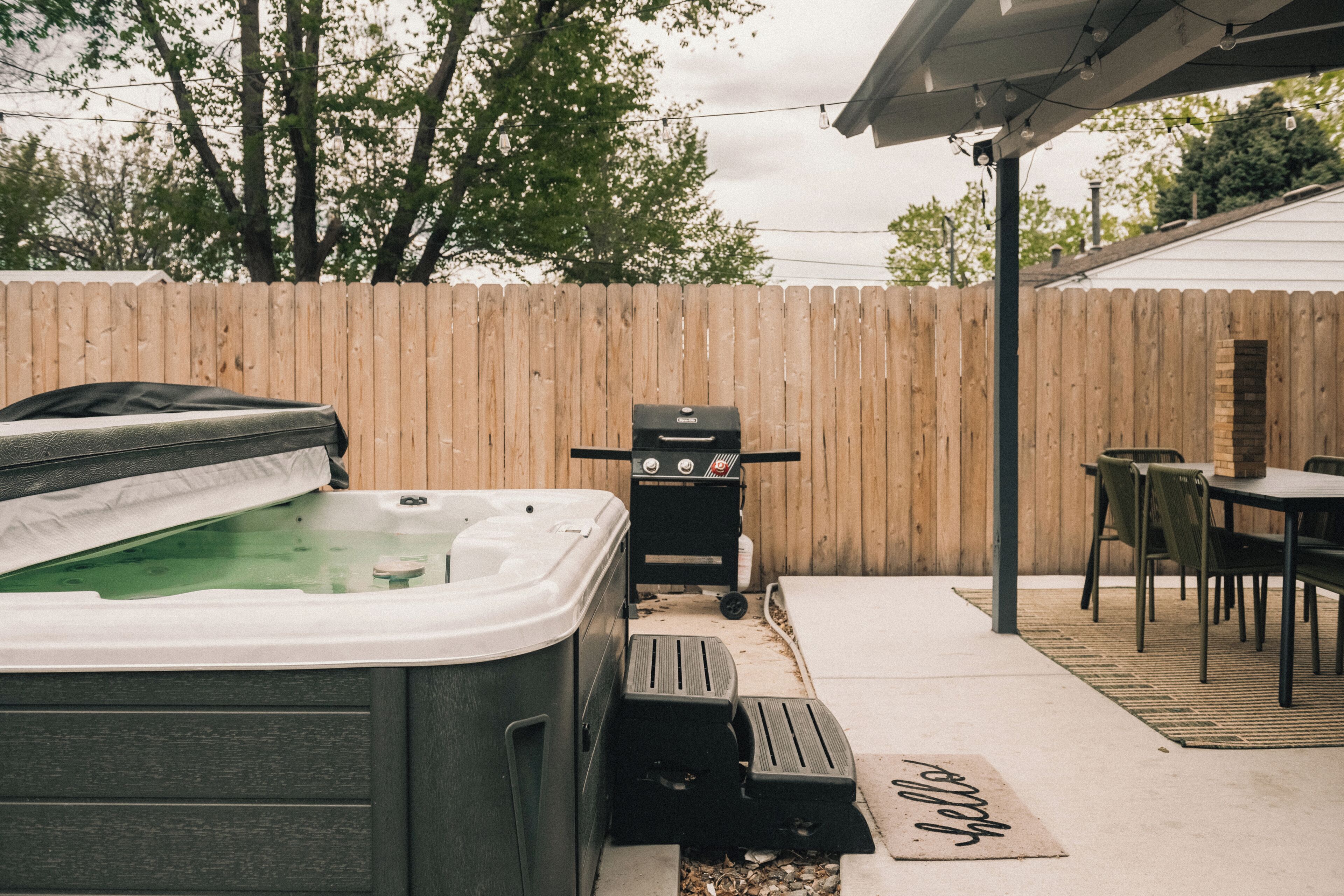 Un jardin avec un jacuzzi, un barbecue et une table de patio.