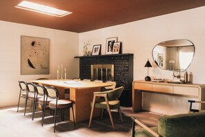 A modern dining area with a wooden table, chairs, a fireplace, and a mirror. - Zenobi Haus (Westminster)