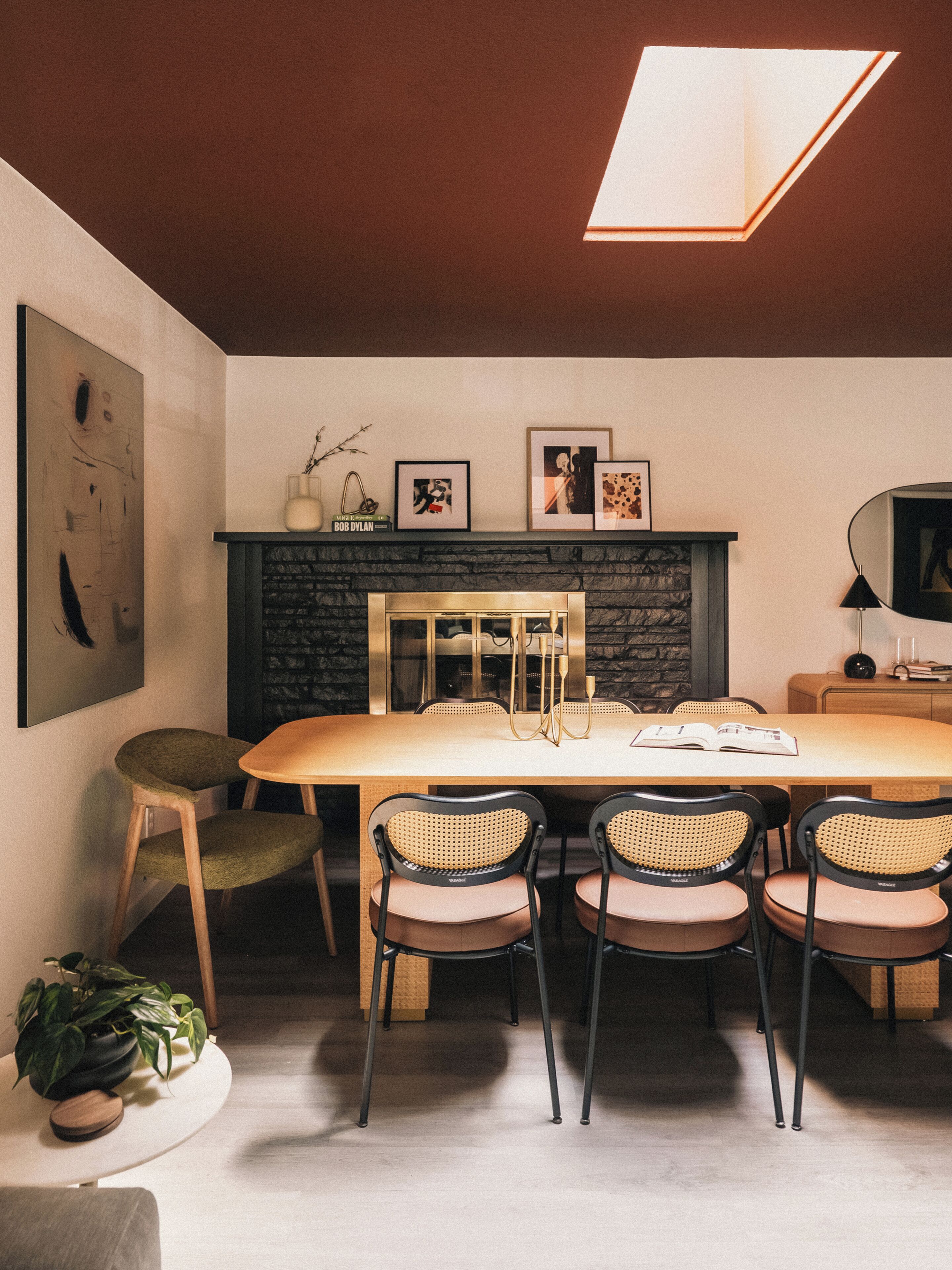 A dining area with a table, chairs, a fireplace, and artwork on the walls.