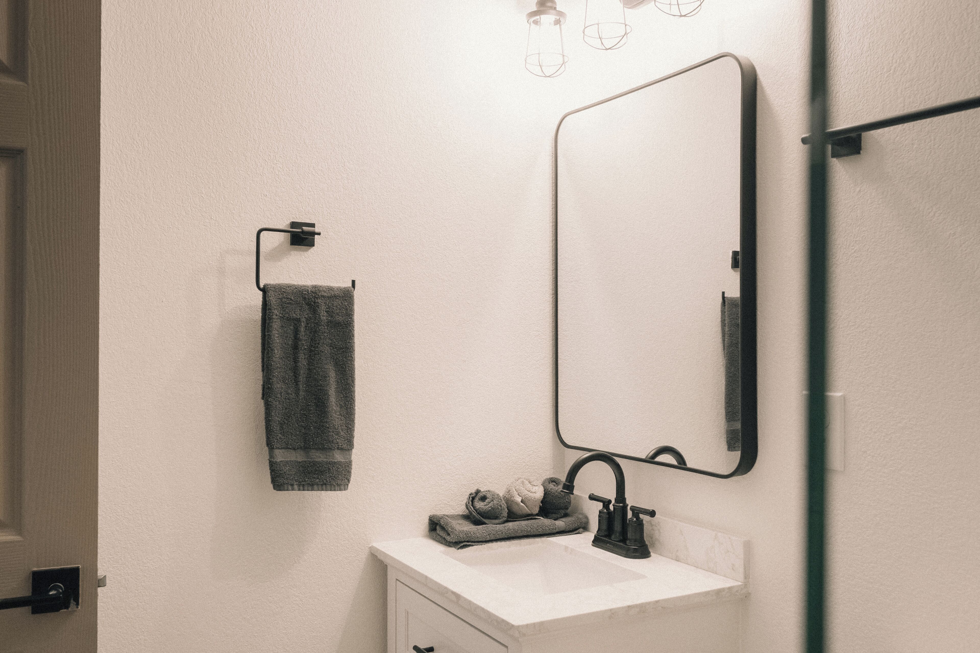 A bathroom with a white sink, a mirror, a towel rack, and a glass shower door.