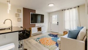 Un salon moderne avec un téléviseur à écran plat, un canapé, une table basse et un tapis à motifs.