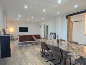 A spacious room with a long dining table, a sofa, and a TV mounted on the wall. - Les Champs Dessus - Sarrey (Sarrey)
