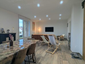 A spacious living area with a dining table, chairs, a sofa, a TV, and a fireplace. - Les Champs Dessus - Sarrey (Sarrey)