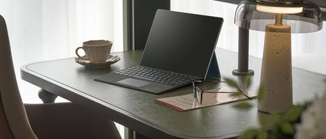 Egy asztalon egy laptop, egy lámpa, egy csésze és egy jegyzetfüzet található.