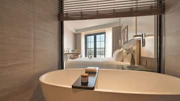 A modern bathroom with a freestanding bathtub, a glass shower enclosure, and a large window providing natural light.
