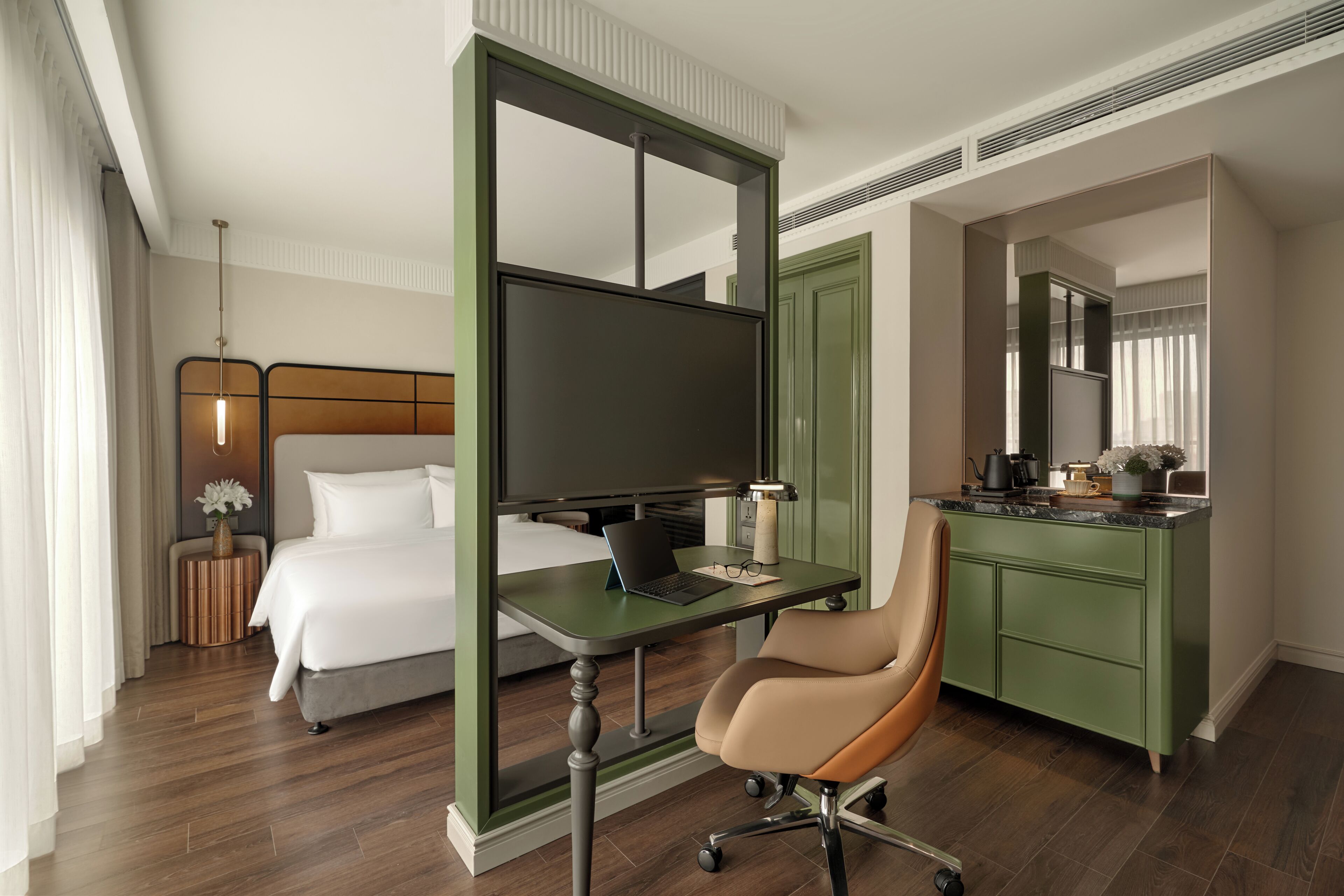 Une chambre d’hôtel avec un lit, un bureau, une chaise, une télévision et des armoires vertes.