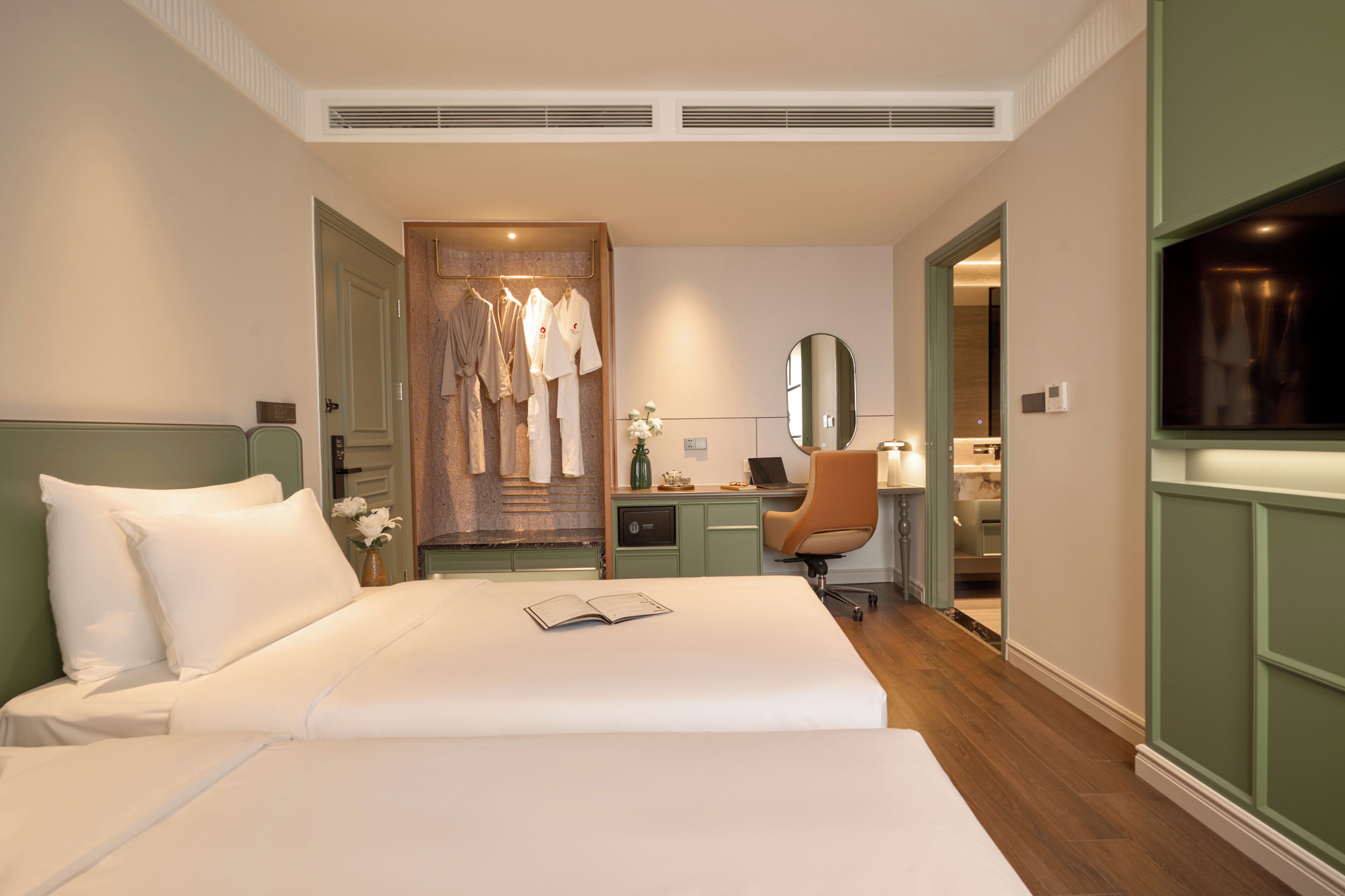 A hotel room with a bed, a desk, a chair, a mirror, and a wardrobe.