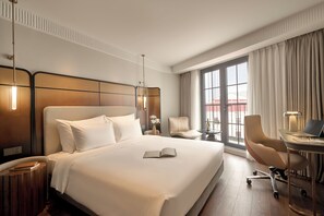 A hotel room with a large bed, a desk with a laptop, a chair, and a view of the outside through a window. - Solaria d'Oriente Hotel (Hanoi)