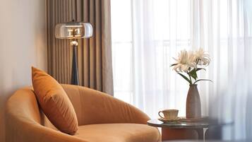 A room with a sofa, a lamp, a vase with flowers, and a table.