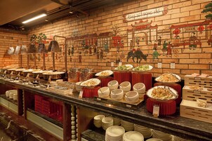 A buffet with various dishes and a wall with cultural artwork.