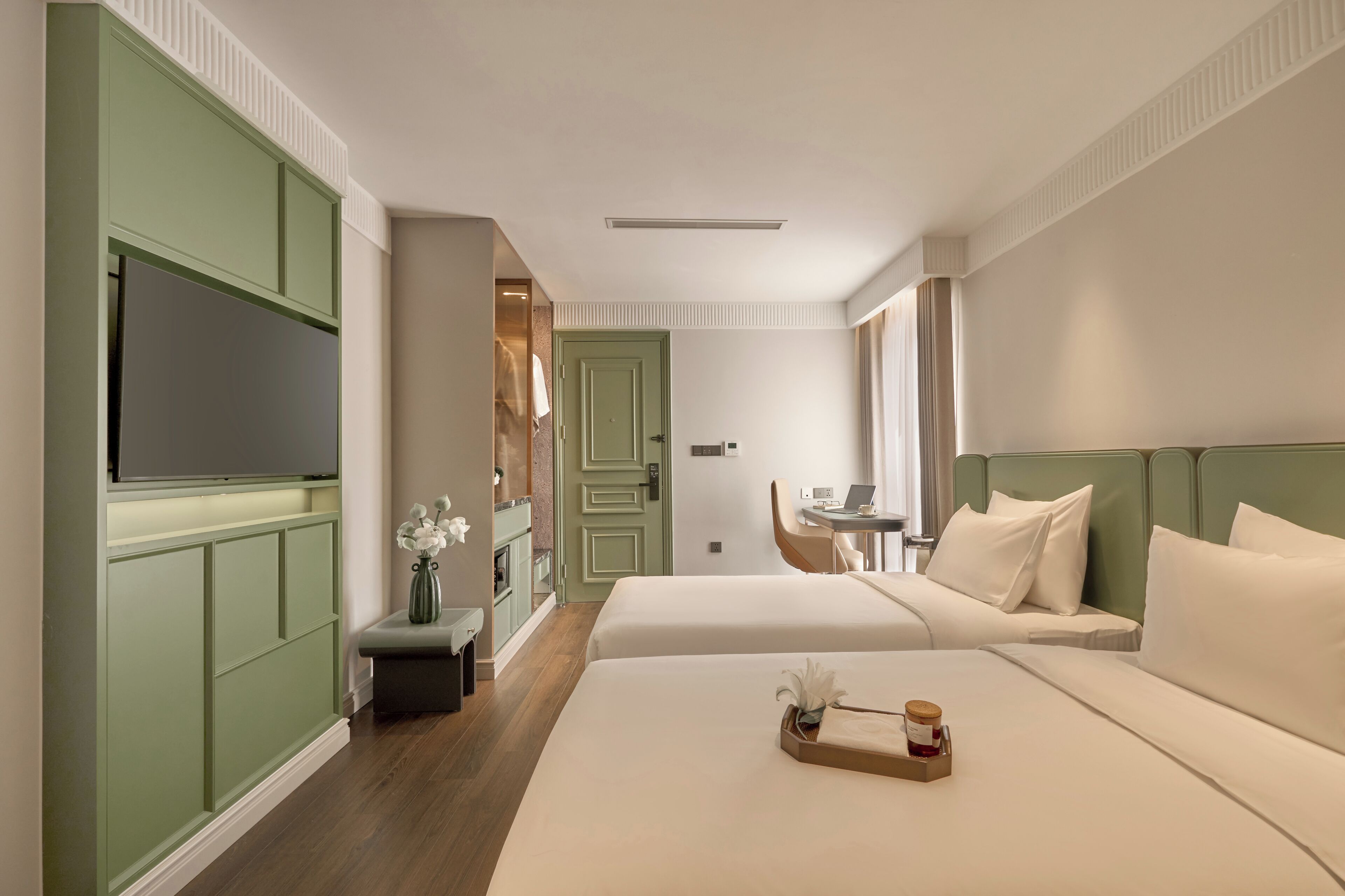 Ein Hotelzimmer mit zwei Betten, einem Fernseher, einem Schreibtisch und einer kleinen Sitzecke.