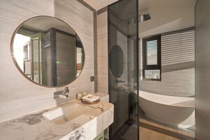 A modern bathroom with a marble sink, a large mirror, and a glass-enclosed shower.