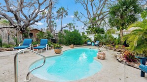 A swimming pool with a metal ladder, surrounded by blue lounge chairs and potted plants. - Coastal Retreat with Private Pool on Manasota Key (Englewood)