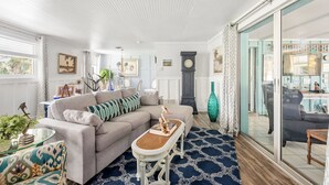 A living room with a sofa, a coffee table, and a large window. - Coastal Retreat with Private Pool on Manasota Key (Englewood)
