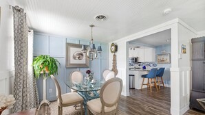 A dining area with a glass table, chairs, a chandelier, and a potted plant. - Coastal Retreat with Private Pool on Manasota Key (Englewood)