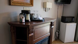 Ein Zimmer mit Kamin aus Holz, einem an der Wand befestigten Fernseher und einem kleinen Kühlschrank.