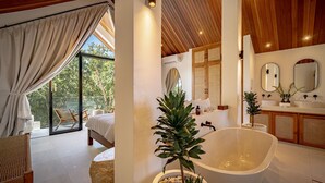 A modern bathroom with a freestanding bathtub, a large mirror, and a potted plant. - Villa Nikki Uluwatu (Uluwatu)