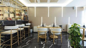 A modern bar area with a marble floor, bar stools, and a glass display of bottles. - Destiny Hotel Tirana (Kashar)