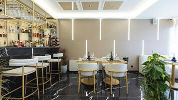 A modern bar area with a marble floor, bar stools, and a glass display of bottles.