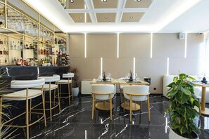 Zona de bar moderna con piso de mármol, taburetes y una vitrina con botellas.