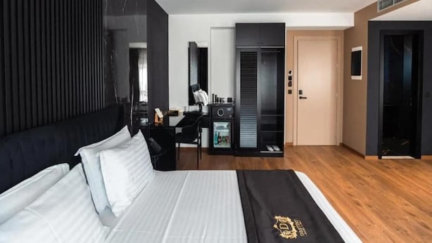 Una habitación de hotel moderna con una cama grande, un escritorio, un armario y una pequeña cocina.