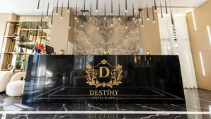 Un mostrador de recepción con encimera de mármol, una araña y el logotipo de 'DESTINY HOTEL & SPA'.