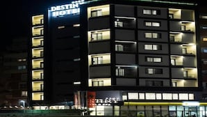 Un hotel de varios pisos con balcones iluminados y un letrero visible que dice 'DESTIN HOTEL'.