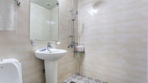 Un baño con lavamanos, espejo, ducha y suelo de baldosas.