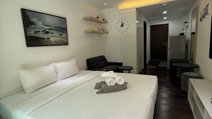 Habitació d'hotel amb un llit, un quadre, un rellotge, una taula de nit i un mirall.