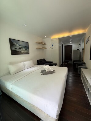 Ein Hotelzimmer mit Bett, Gemälde, Uhr, Schreibtisch und Spiegel.