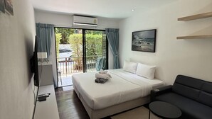 Habitació d'hotel moderna amb llit, sofà, taula petita i televisió.