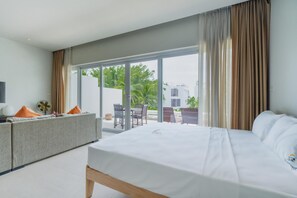Habitación de hotel moderna con cama, sofá, ventilador y vistas al exterior.