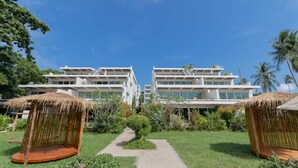 Ett modernt hotell med en central gångväg, tvåvåningsbyggnader och byggnader med halmtak.