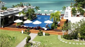 Ett semesterhotell med en swimmingpool, solstolar och utsikt över havet.
