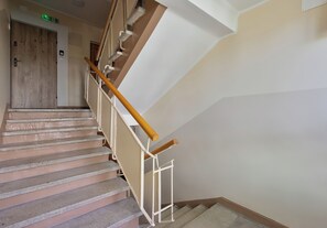 Eine Treppe mit Handlauf, Teppichstufen und einer Holztür am Oberende.