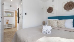 Ein Schlafzimmer mit einem Bett, einem Nachttisch, einer Wandlampe und einer Tür zu einem anderen Raum.