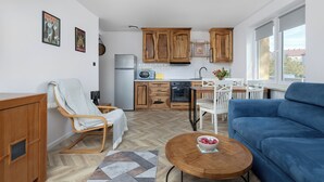 Eine moderne Küche mit Holzausbau, ein Essbereich mit blauem Sofa und ein Fußboden mit Zickzackmuster.