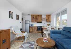 Eine moderne Küche mit Holzausbau, ein Essbereich mit blauem Sofa und ein Fußboden mit Zickzackmuster.