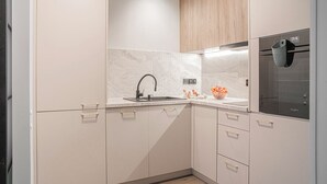 A modern kitchen with a sink, countertop, and a refrigerator. - Przymorze Kaszmirowy Apartment (Gdańsk)