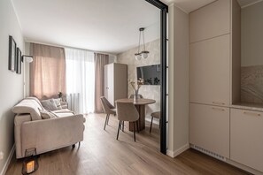 Un salon moderne comprenant un canapé, une table à manger, des chaises et un coin cuisine avec des placards.