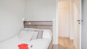 A bedroom with a bed, bedside lamp, and a door leading to another room. - Przymorze Kaszmirowy Apartment (Gdańsk)