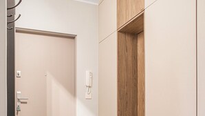 A hallway with a door, a coat rack, a light switch, and a wooden cabinet. - Przymorze Kaszmirowy Apartment (Gdańsk)