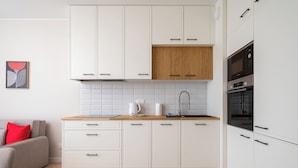 A modern kitchen with white cabinets, a wooden countertop, and a built-in oven. - Warszawa Rakowiec Deluxe Apartment (Warszawa)