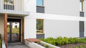 A modern building with a balcony, a door, and a small garden area. - Warszawa Rakowiec Deluxe Apartment (Warszawa)