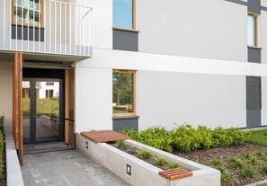 A modern building with a balcony, a door, and a small garden area. - Warszawa Rakowiec Deluxe Apartment (Warszawa)