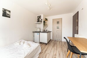 A compact room with a bed, a small kitchenette, a dining table with chairs, and a door leading to another room. - Gdynia Morska Horizon Studio (Gdynia)
