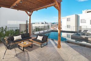A rooftop terrace with a pool, outdoor seating, and a view of the city. - Luxury villa Natali w pool, terrace and sea view (Podstrana)