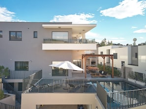 A modern multi-story building with a rooftop pool, outdoor seating, and a pergola. - Luxury villa Natali w pool, terrace and sea view (Podstrana)
